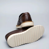 Par do modelo Mocassim Tratorado Siena Ripple, na cor marrom, com um dos solados voltado para a câmera.