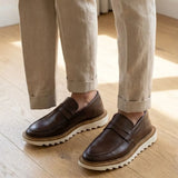 Mocassim Tratorado Siena Ripple na cor marrom, usado com calça clara de barra dobrada.
