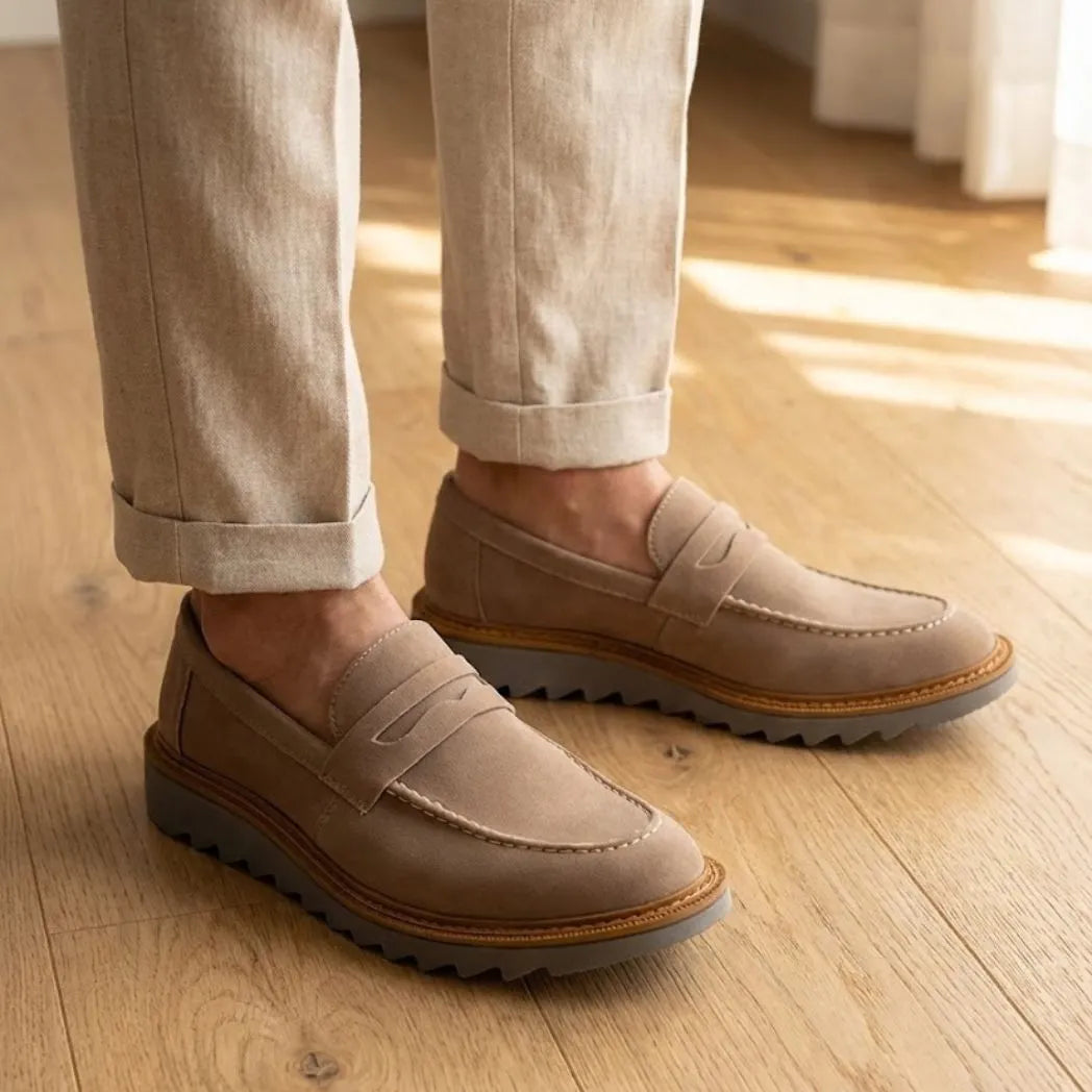 Mocassim Tratorado Taupe de Camurça na cor bege, usado com calça clara de barra dobrada.