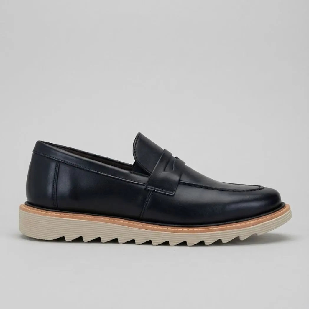 Mocassim Tratorado de Couro Verona: modelo preto de perfil, com faixa frontal, borda marrom e sola bege com sulcos profundos.