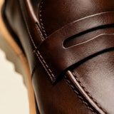 Mocassim Tratorado de Couro Verona Marrom: detalhe da faixa penny em couro marrom, recorte e costuras do cabedal.
