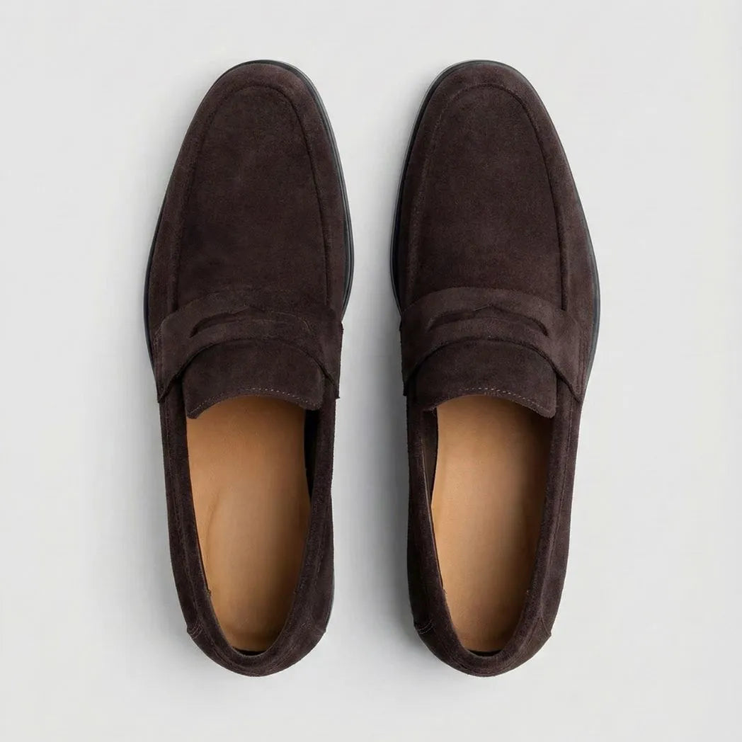 Mocassim Turim Loafer Camurça Marrom: par marrom-escuro visto de cima, mostrando a faixa frontal e o interior claro.