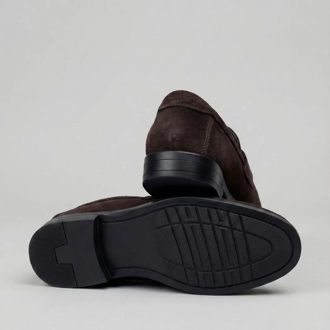 Mocassim Turim Loafer Camurça Marrom: par marrom-escuro com um sapato virado, mostrando a sola preta.