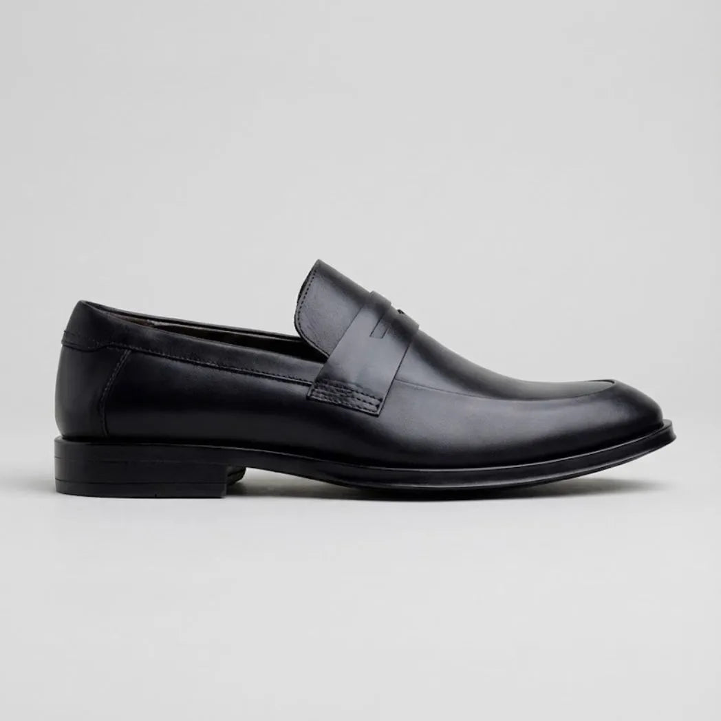 Mocassim Turim Loafer Couro: modelo preto de perfil, com faixa frontal e sola preta.