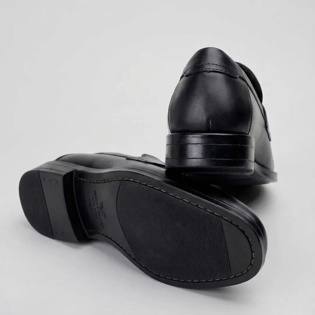 Mocassim Turim Loafer Couro: par preto com um sapato virado, mostrando a sola preta.
