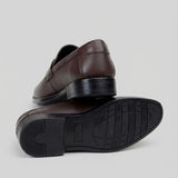 Mocassim Turim Loafer Couro: par marrom-escuro com um sapato virado, mostrando a sola preta com sulcos.