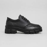 Mocassim Vanguard Tratorado: modelo preto de perfil, com cadarços e sola preta espessa com sulcos profundos.