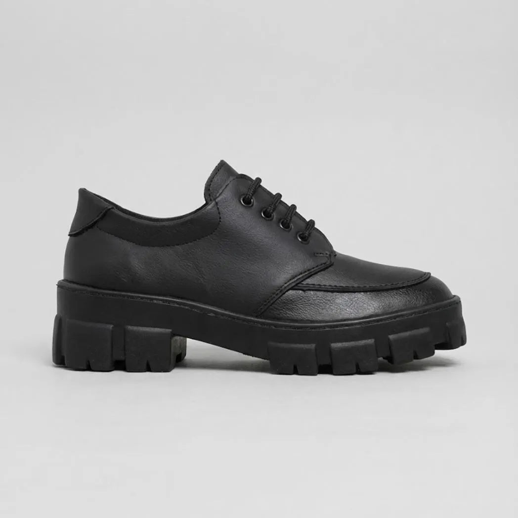 Mocassim Vanguard Tratorado: modelo preto de perfil, com cadarços e sola preta espessa com sulcos profundos.