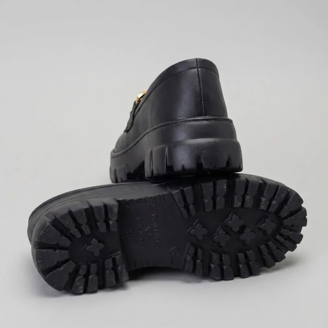 Par do modelo Mocassim Vanguard Tratorado, na cor preto, com um dos solados voltado para a câmera.