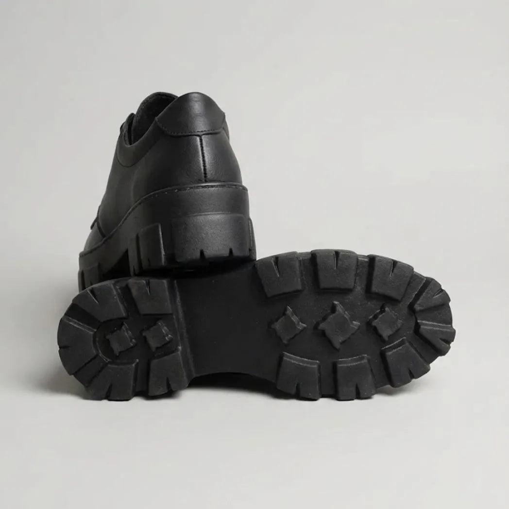 Par do modelo Mocassim Vanguard Tratorado, na cor preto, com um dos solados voltado para a câmera.