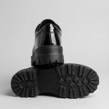 Par do modelo Mocassim Vanguard Tratorado, na cor preto, com um dos solados voltado para a câmera.