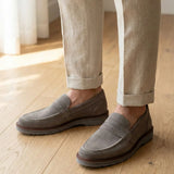 Mocassim de Camurça Monaco Edition: par cinza usado com calça bege dobrada na barra.