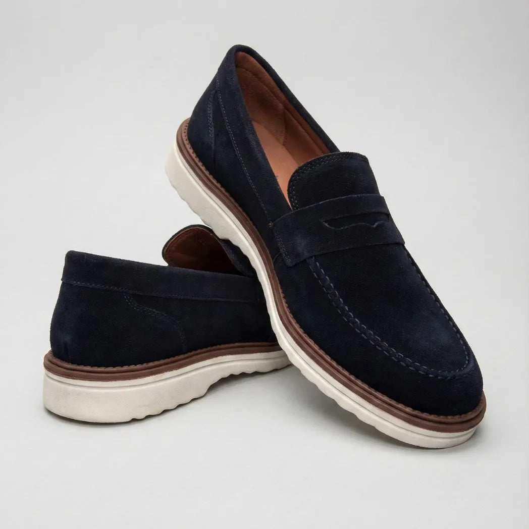 Mocassim de Camurça Monaco Edition: par azul-escuro em posição cruzada, com faixa frontal e sola clara.