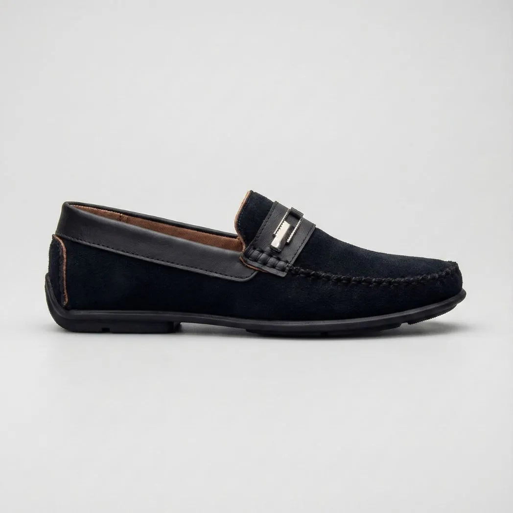 Mocassim de Camurça Titan Coffee: modelo preto de perfil, com ferragem retangular na faixa frontal e sola preta.