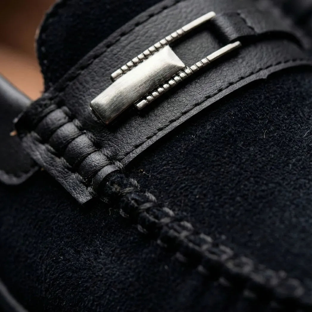 Mocassim de Camurça Titan Coffee: detalhe da ferragem retangular prateada, da faixa frontal e da textura preta.