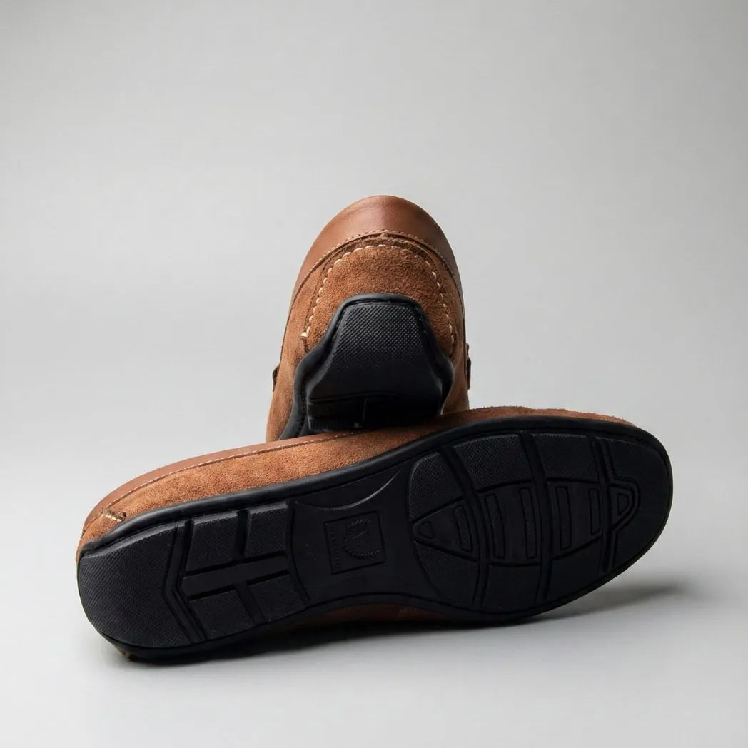 Mocassim de Camurça Titan Coffee: par marrom com um sapato virado, mostrando a sola preta com sulcos.