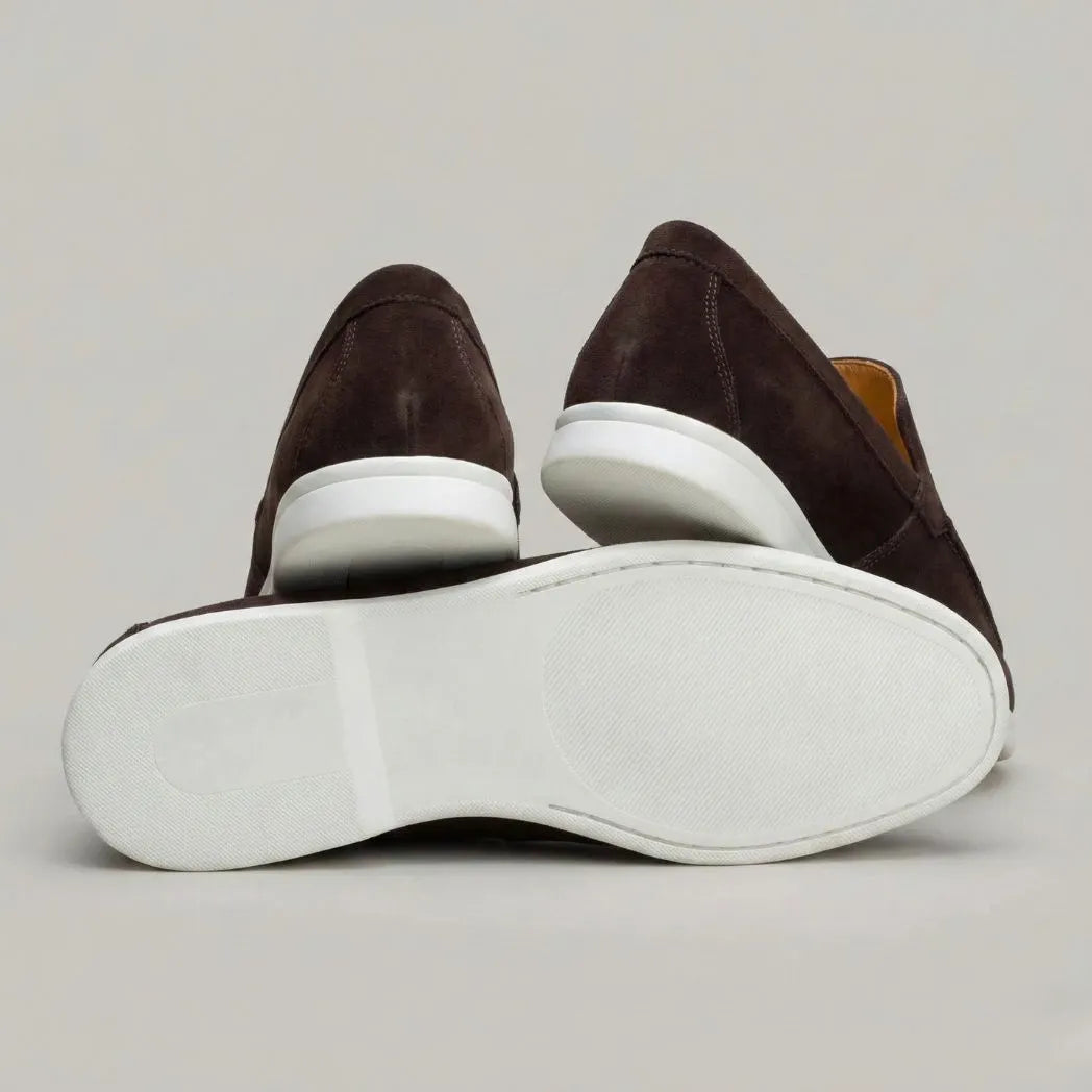Mocassim de Camurça de Lebre: par marrom-escuro com um sapato virado, mostrando a sola branca.