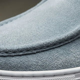 Mocassim de Camurça: detalhe da textura azul-clara, da costura frontal e da borda da sola branca.