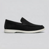 Mocassim de Camurça: modelo preto de perfil, com sola branca.